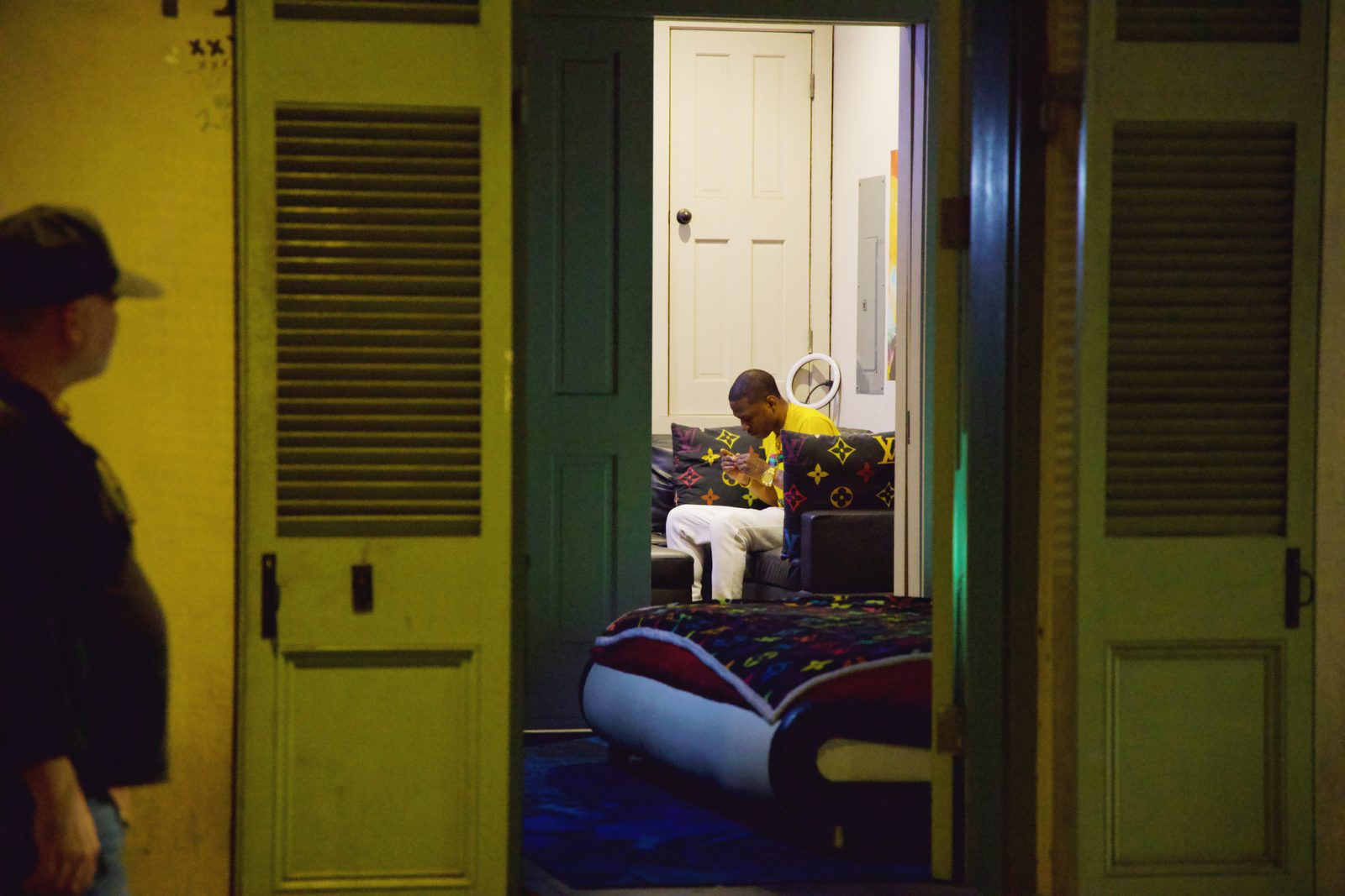 Figures in a doorway washed in yellow and green light at night — New Orleans
