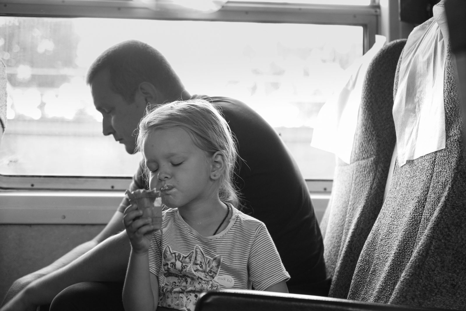 Black-and-white close view of a man holding a young child inside a train carriage — Lake Baikal