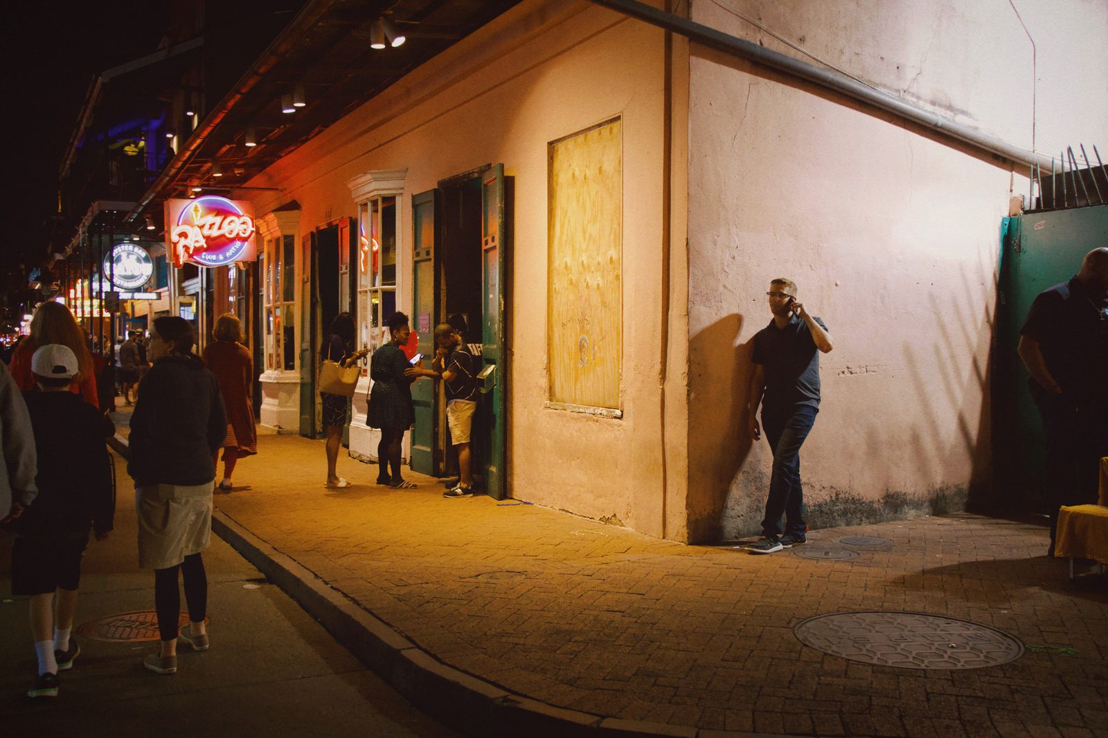 A lone man standing on a sidewalk at night beneath street lights — New Orleans